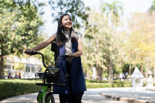 Asian businesswoman in bicycle go to work at office. Bike commuting, happy businesswoman using eco transport, Concept of eco lifestyle.