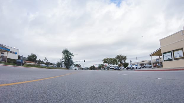 Santa Maria, California, USA-December 6, 2022-Vehicle navigates the streets of Morro Bay, California, during a cloudy winter day. The atmosphere is moody and serene as the overcast sky casts a soft light on the charming buildings and quiet streets of this coastal town.