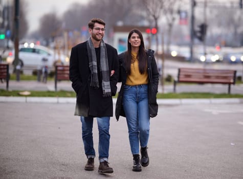 A romantic couple embraces in a tender hug as they stroll through the city streets, enjoying leisure time together in each other's company.