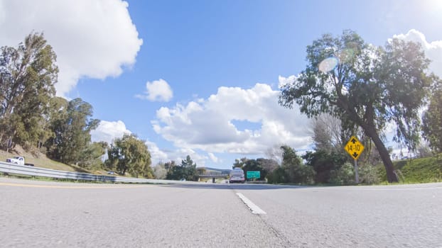 Santa Maria, California, USA-December 6, 2022-On a clear winter day, a car smoothly travels along Highway 101 near Santa Maria, California, under a brilliant blue sky, surrounded by a blend of greenery and golden hues.