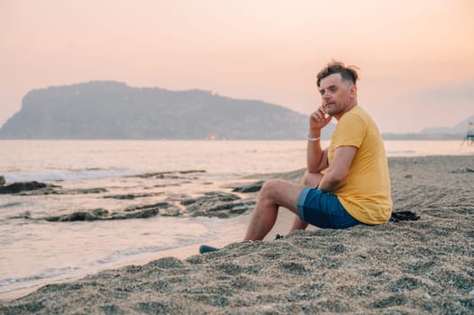 Man sits on the beach and looks at the sea in Alanya city, Turkey. Travelling or vacation concept