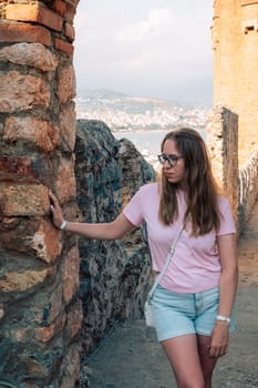 Woman at Fortress ruins of the historical Red Tower - Kizil Kule, in Alanya Castle. The Red Tower is the symbol of the Alanya city, and the famous touristic place, Turkey (Turkiye).