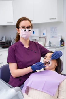 Portrait of young female doctor performs teeth treatment to patient.