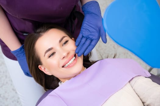 Dentist demonstrates the result of teeth whitening, while happy patient looks in the mirror