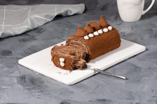 Chocolate roll on a white wooden cutting board.
