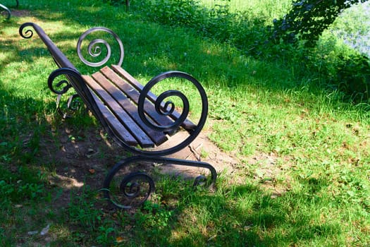 Photo a wooden brown bench in the park. A place to relax. A day in summer.
