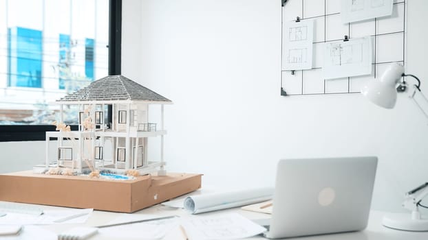 Closeup image of modern house model, laptop, blueprint and architectural equipment placed on table at modern meeting room. Creative business living and design concept. Architect table. Immaculate.