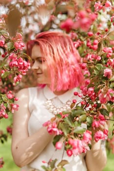 Young girl with pink hair in an Apple orchard. Beautiful young girl in a blooming garden of pink Apple trees