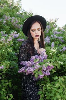 A fashionable girl with dark hair, a spring portrait in lilac tones in summer. Bright professional makeup