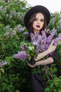 A fashionable girl with dark hair, a spring portrait in lilac tones in summer. Bright professional makeup