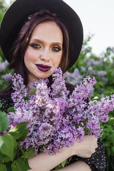 A fashionable girl with dark hair, a spring portrait in lilac tones in summer. Bright professional makeup