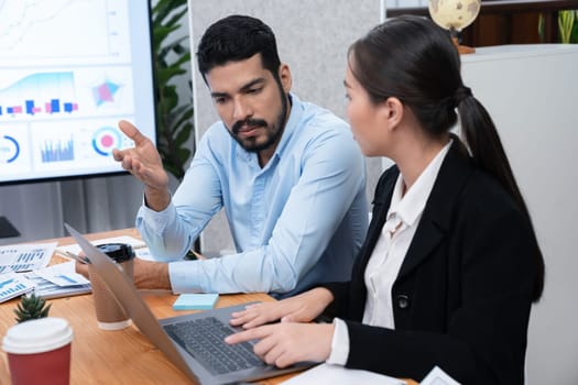 Multiracial analyst team use BI dashboard data to analyze financial report on meeting table. Group of diverse business people utilize data analysis by FIntech for business marketing decision. Concord