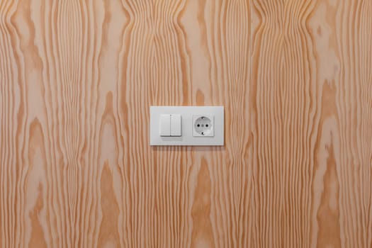 A simple yet elegant light switch and power socket mounted on a wood-patterned wall