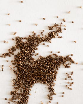 Buckwheat seeds spread in random, artistic patterns on a plain white surface