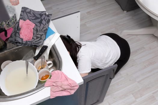 Woman trying to fix a siphon in the kitchen at home. Housework concept.