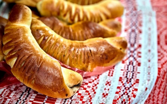 A close-up of freshly baked homemade puff pastry horns filled with rich chocolate cream on a red checkered tablecloth. Golden brown and flaky pastry, perfect for a sweet breakfast or snack.