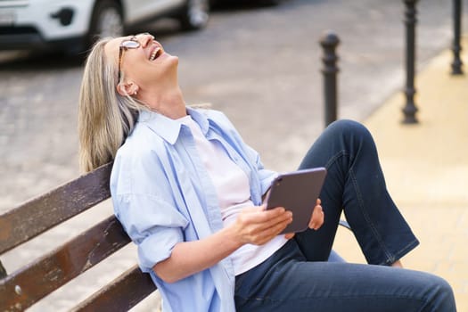 A woman sitting on a bench, gazing upwards at an object or view in front of her.