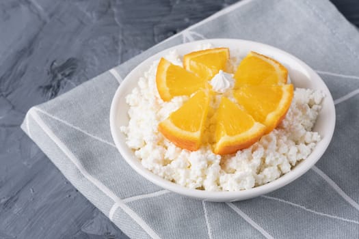 Fresh cottage cheese in white bowl with orange pieces. Copy space.