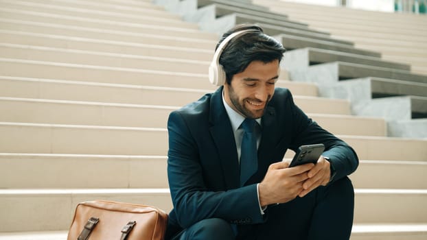 Smart business man listening and enjoy music while wear headphone. Profession project manager smiling while getting good news, getting promotion, increasing sales. Relaxing man enjoy music. Exultant.