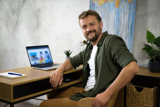 A man sits at a desk, working on a laptop computer.