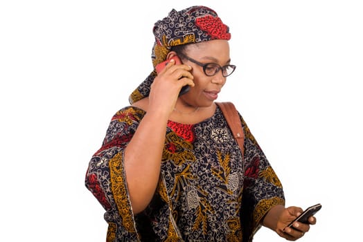 african mature woman in loincloth standing on white background communicating with mobile phone while smiling.