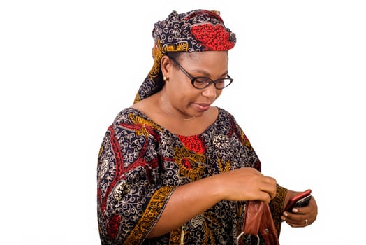 african mature woman in loincloth standing on white background looking at handbag.