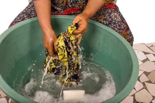 mature african woman in loincloth sitting doing laundry.