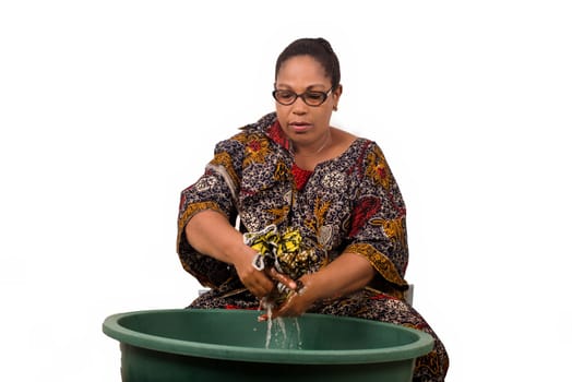 mature african woman in loincloth sitting doing laundry.