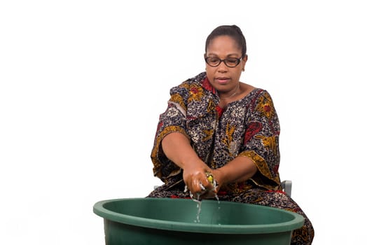 mature african woman in loincloth sitting doing laundry.