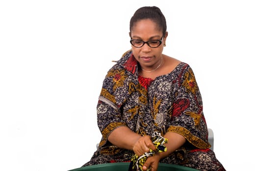 smiling african woman sitting and washing clothes in a big green bowl isolated on white background.