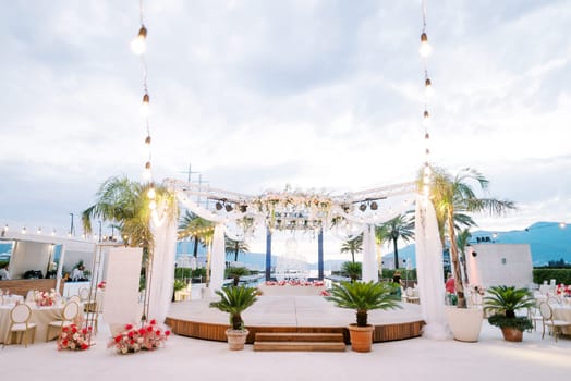 Round stage decorated with garlands stands between the laid tables. High quality photo