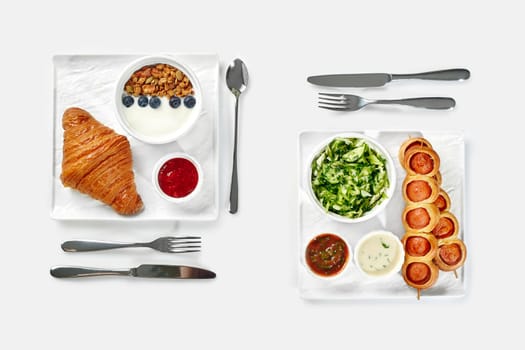 Inviting breakfast for two featuring flaky croissant, granola with yogurt and berry jam, alongside sausage rolls in brioche on skewers, fresh vegetable salad and sauces served on white trays