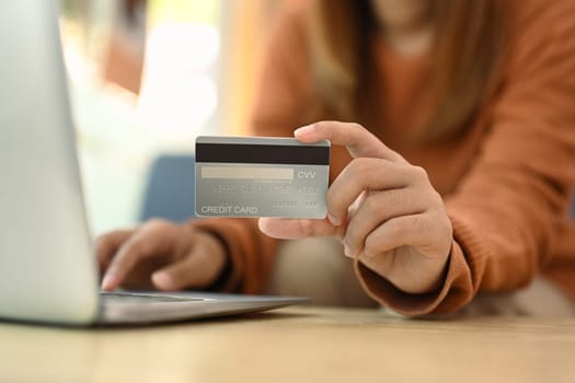 Woman hand holding credit card and using laptop. Banking transaction and shopping online concept.