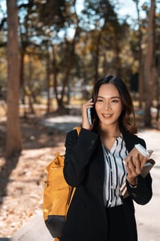 Portrait of beautiful businesswoman walking in an autumn park and talking on mobile phone.