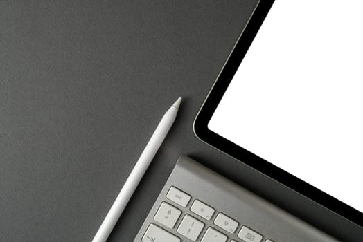 Tablet with blank screen, keyboard and stylus pen on dark gray background