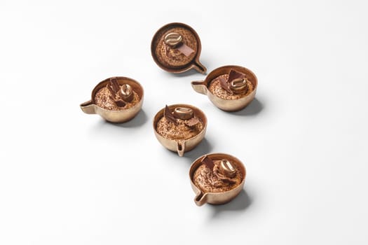 Designer exquisite chocolate candies in shape of miniature coffee cups with delicate coffee filling on white background