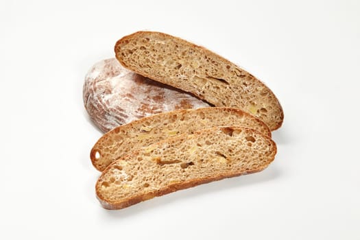 Whole and sliced loaves of wheat bread with crispy browned crust and airy texture displayed against white background. Bakery and breadmaking concept