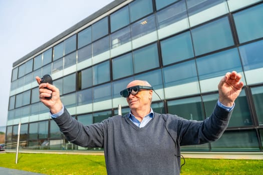 Aged man using augmented mixed vision headset and gesturing standing outside a financial building