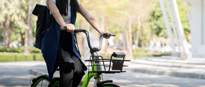 Asian businesswoman in bicycle go to work at office. Bike commuting, happy businesswoman using eco transport, Concept of eco lifestyle.