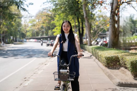 Asian businesswoman in bicycle go to work at office. Bike commuting, happy businesswoman using eco transport, Concept of eco lifestyle.