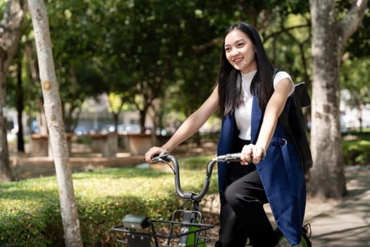 Asian businesswoman in bicycle go to work at office. Bike commuting, happy businesswoman using eco transport, Concept of eco lifestyle.