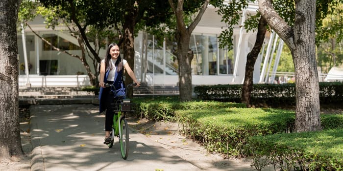 Asian businesswoman in bicycle go to work at office. Bike commuting, happy businesswoman using eco transport, Concept of eco lifestyle.