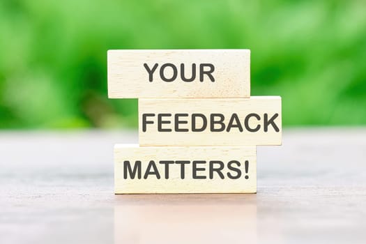 YOUR FEEDBACK MATTERS Back to school the inscription on wooden bars against a background of green plants is out of focus