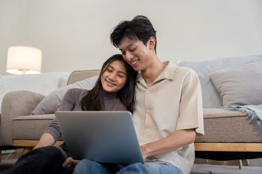 Happy couple asian with laptop on floor in the living room at home.