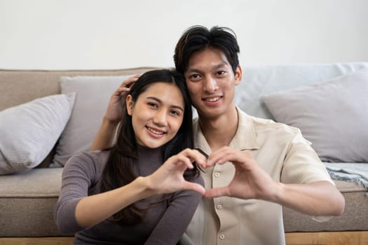 Lovely young couple asian is making heart sign with hands at home. Valentine day celebration.