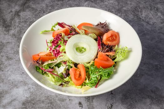 Green vegan salad from green leaves mix and vegetables. Top view on gray stone table.,