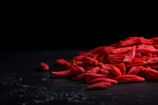 New goji berries on black background. Fruit with water drops. Generate Ai