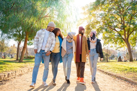 Cheerful group of friends walking outdoors in the park having fun together. Concept of community, youth lifestyle and friendship. High quality photo