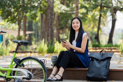 asian young businesswoman use smart phone while commuting in city. Eco friendly.