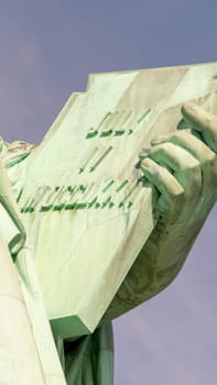 Declaration of Independence in the hand of the statue of liberty with the date of its adoption on